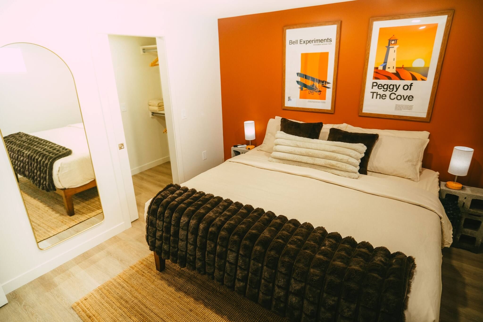 Une chambre d’hôtel avec un lit, un miroir, une table de chevet et deux tableaux encadrés au mur.