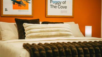 A neatly made bed with white linens and a brown throw blanket, accompanied by two pillows, one white and one brown.