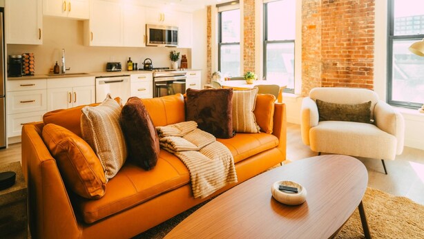A modern living room with a leather sofa, a wooden coffee table, and a brick wall. - Free Parking Historic 1BR plus Den DT Halifax (Halifax)