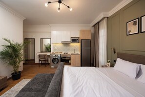 A compact hotel room with a bed, a small kitchenette, a washing machine, and a dining area. - Amazing Deal at 77 by Spacey #13 (cairo)