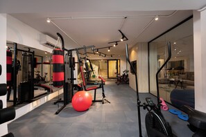 A gym with exercise equipment, a punching bag, and a stationary bike. - Amazing Deal at 77 by Spacey #13 (cairo)