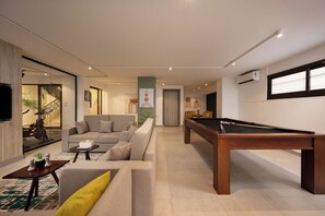 A modern living room with a pool table, a sofa, and a staircase leading to another level. - Amazing Deal at 77 by Spacey #13 (cairo)