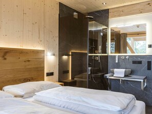A modern bedroom with a wooden headboard, a glass shower enclosure, and a marble-tiled vanity. - Superior Chalet #12 With Sauna & Hot Tub (Stadl-Predlitz)