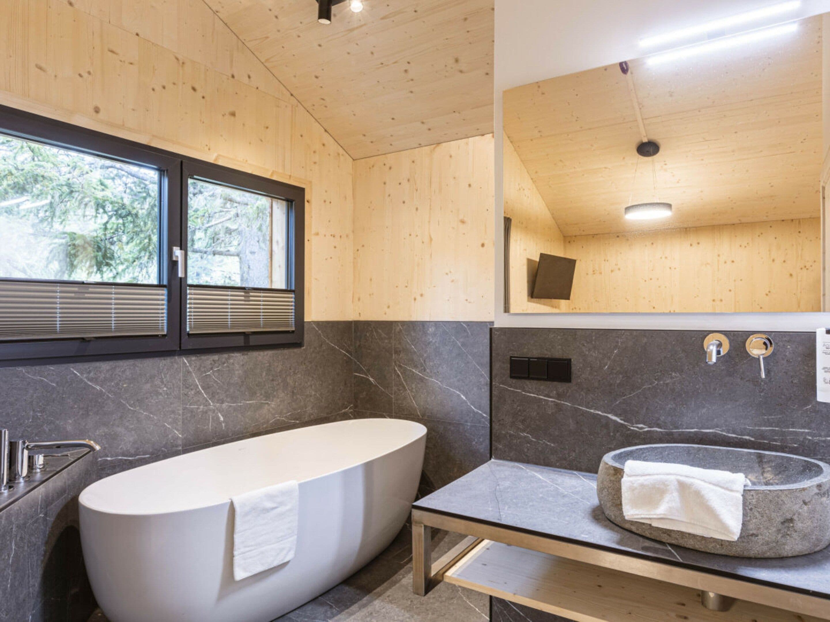 Ein modernes Badezimmer mit einer freistehenden Badewanne, einem Steintonne und einem großen Spiegel.