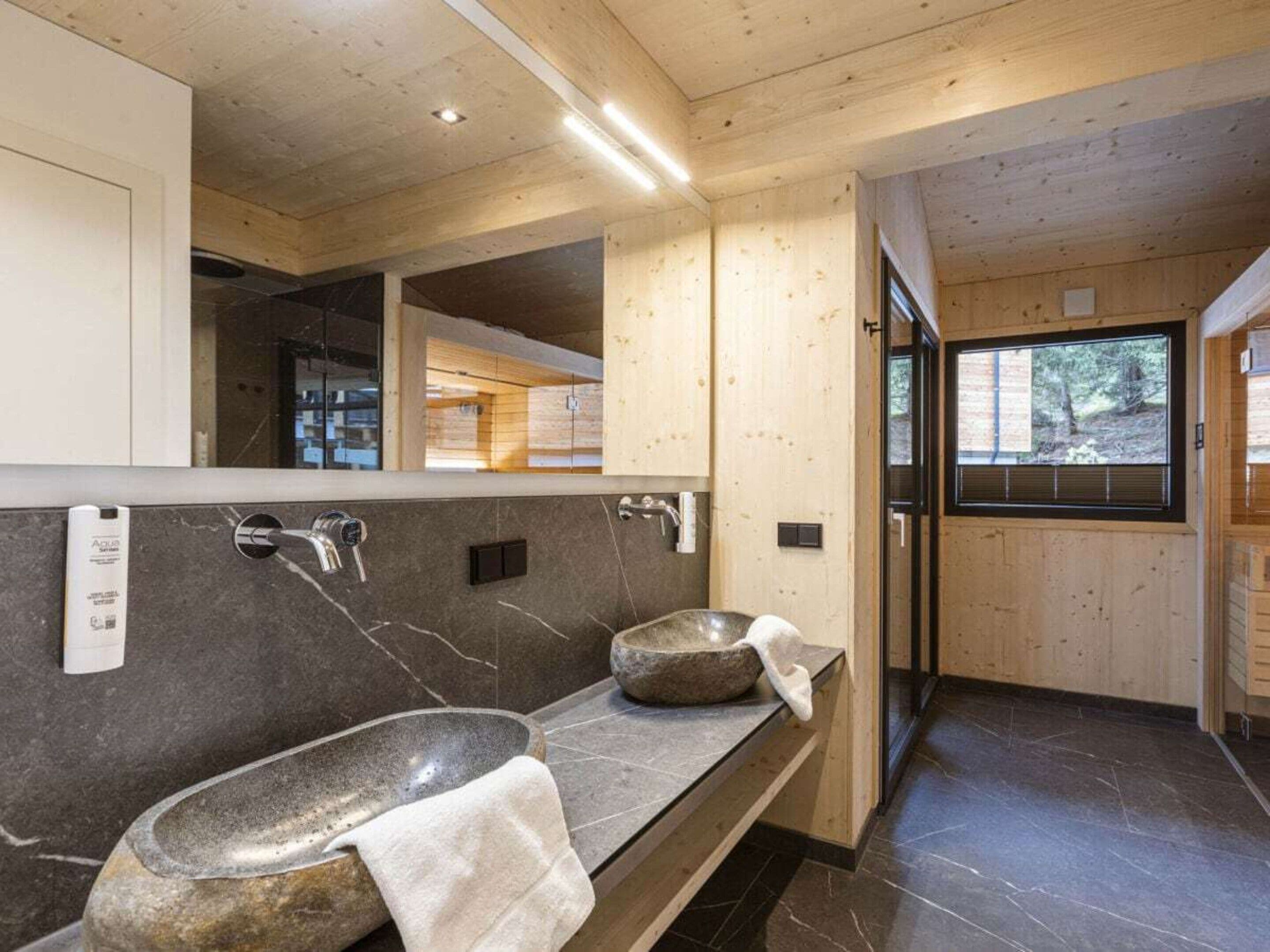 Ein modernes Badezimmer mit einem Steintonne, einem großen Spiegel und Blick ins Freie.