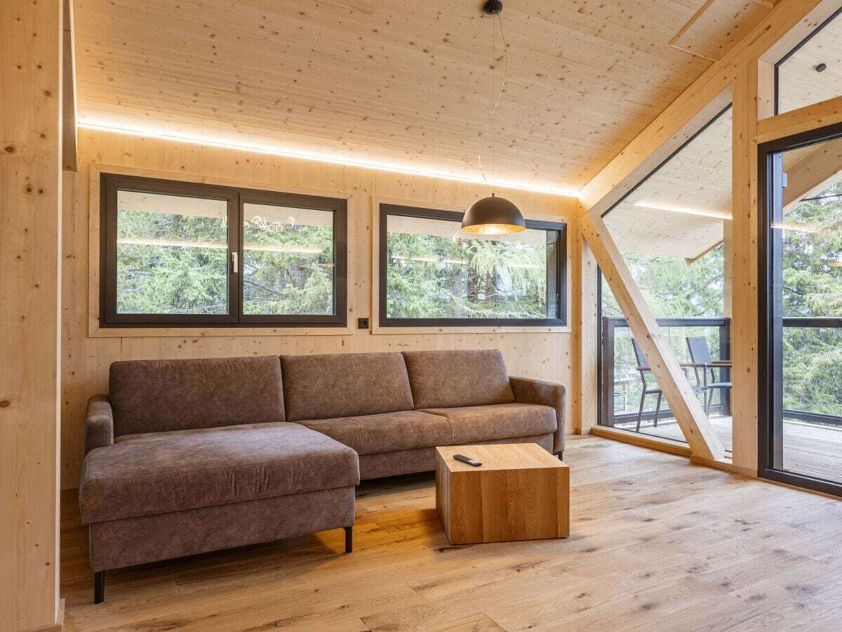 Een modern interieur met een houten plafond, grote ramen, een bank en een salontafel.