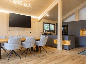 A modern interior with a dining area, kitchen, and a large flat-screen TV mounted on the wall. - Superior Chalet #12 With Sauna & Hot Tub (Stadl-Predlitz)