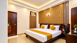 A hotel room with a large bed, a desk, a chair, a wall-mounted air conditioner, and a decorative wall panel. - HOTEL JAD STAR RESIDENCY (New Delhi)