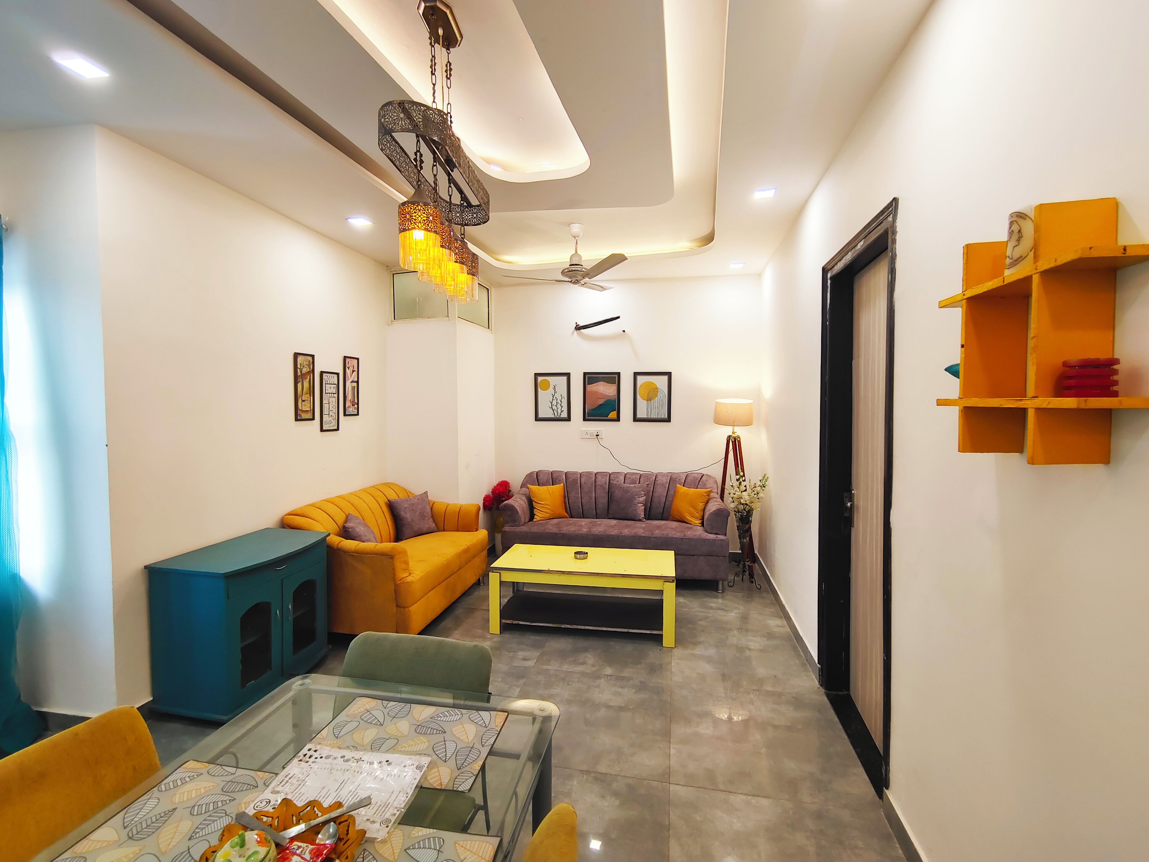 A modern living room with a sofa, coffee table, and a glass-top table with items on it.