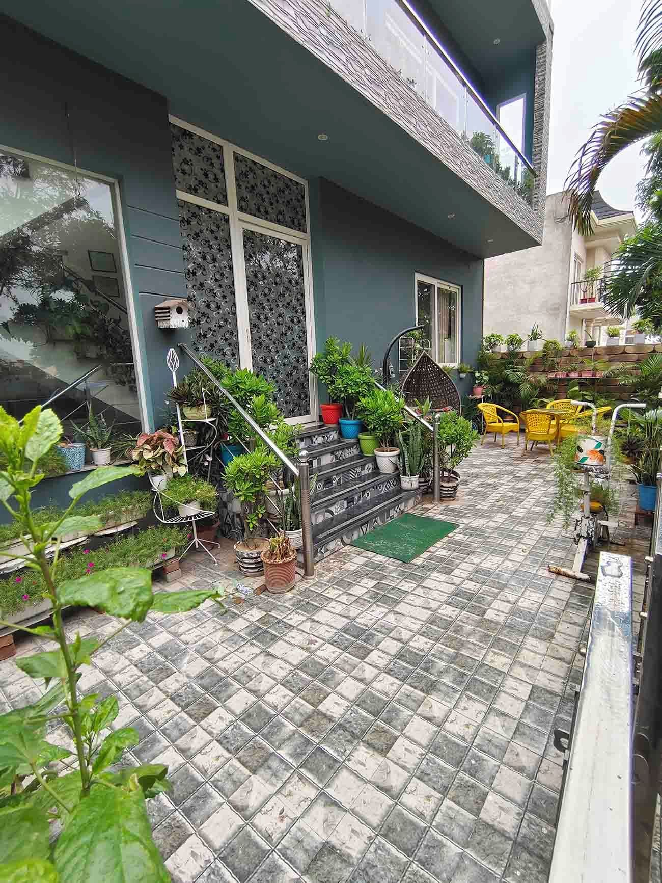 A residential building with a tiled patio, potted plants, and outdoor furniture.