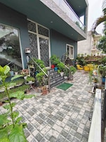 Un edificio residencial con un patio empedrado, plantas en macetas y mobiliario de exterior.