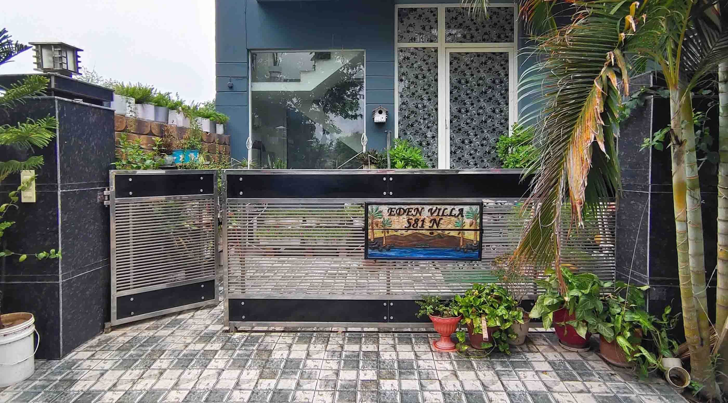 A gated entrance with a sign reading 'EDEN VILLA 581 NW' and a tiled patio area with potted plants.
