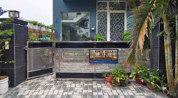 A gated entrance with a sign reading 'EDEN VILLA 581 NW' and a tiled patio area with potted plants.