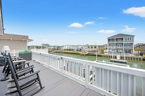 Een pand aan het water met een terras, buitenmeubels en uitzicht op het water en aangrenzende gebouwen.