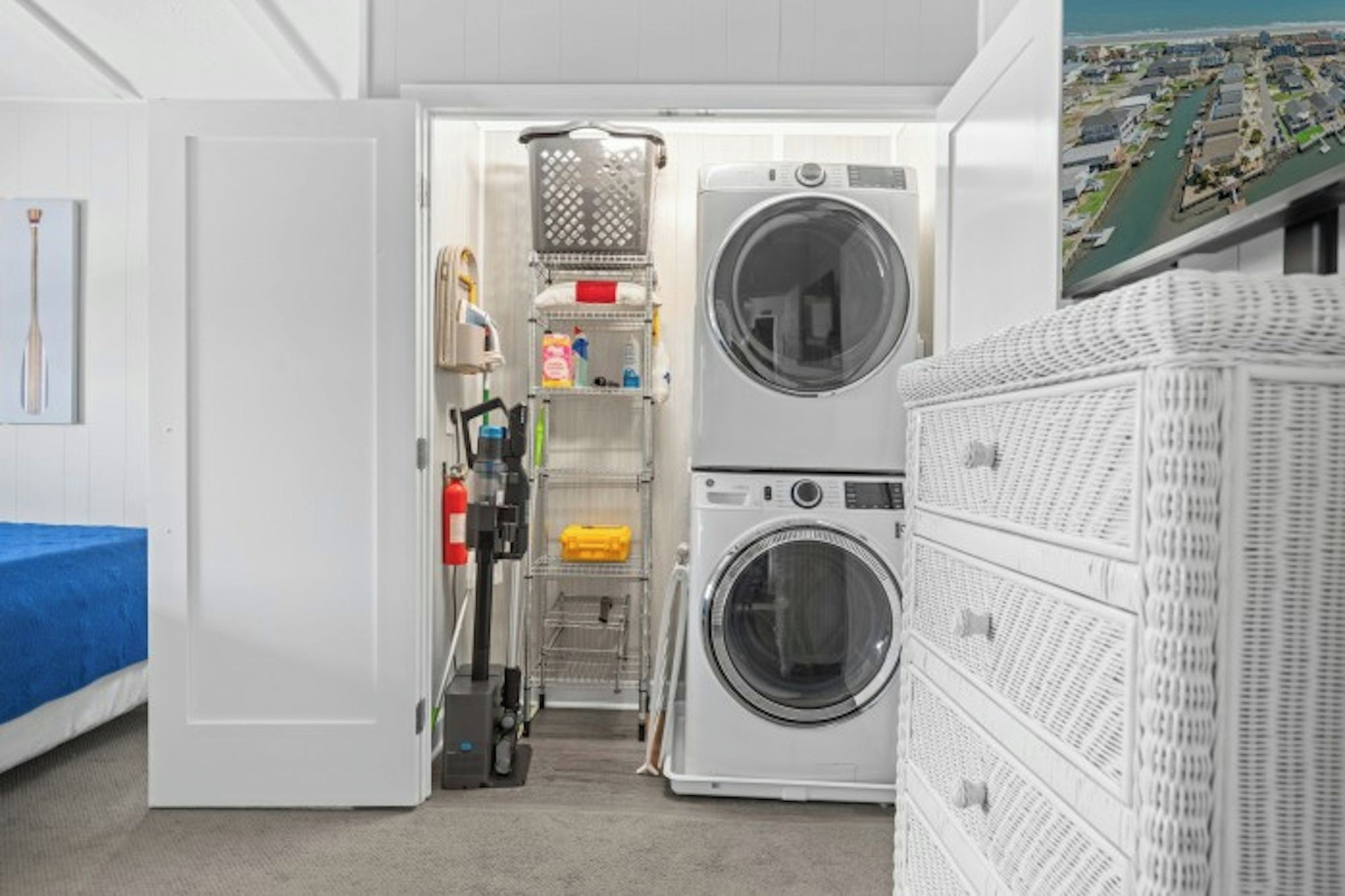 A laundry room with two stacked washing machines, shelves with cleaning supplies, and a fire extinguisher.