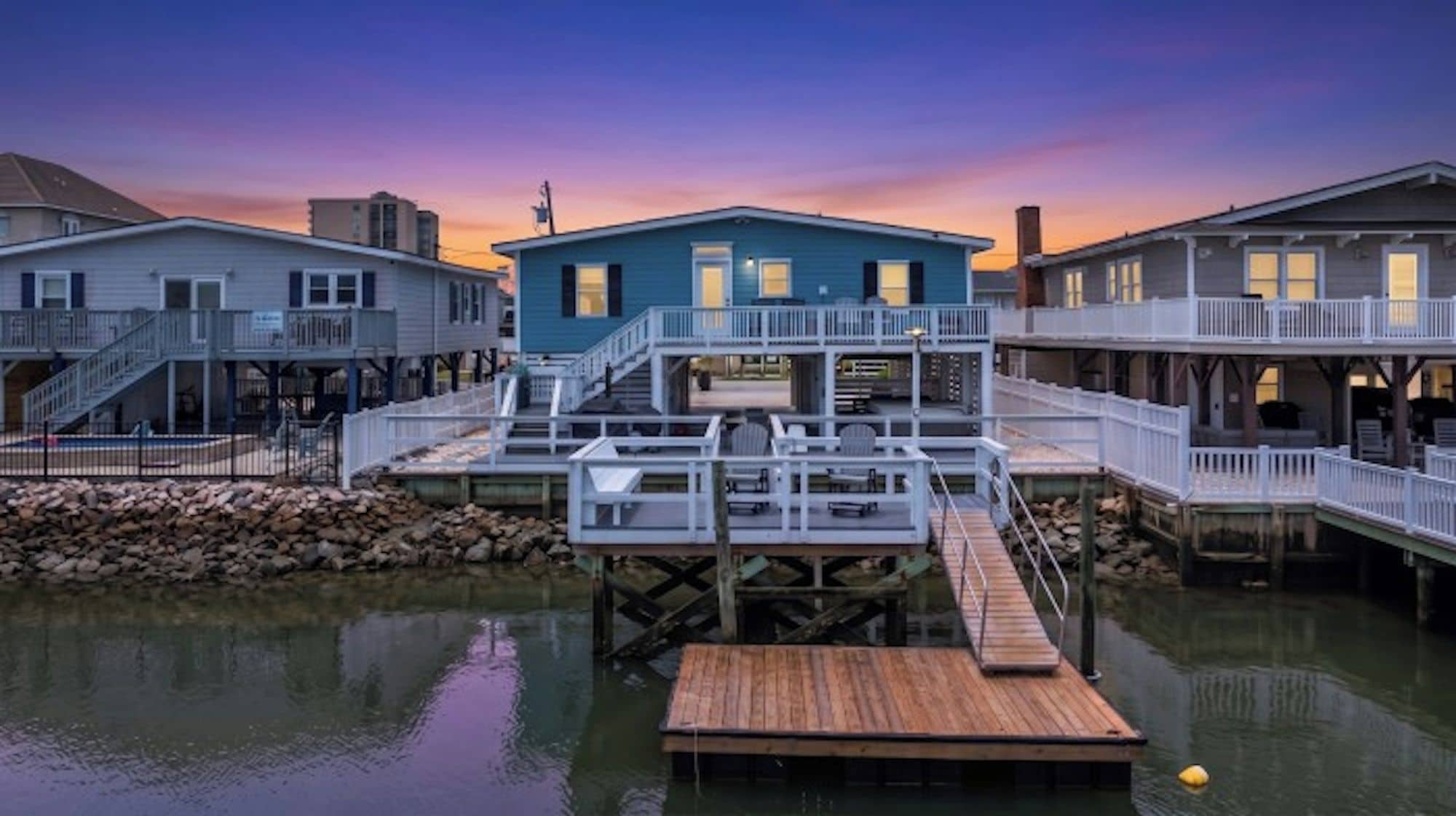 A waterfront property with a dock, a blue building, and a white building with a balcony.