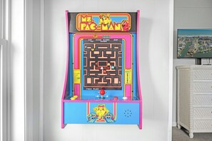 Een Pac-Man spelautomaat met een doolhof, scorebord en een personage onderin.