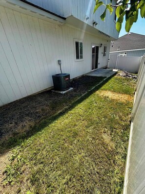 A residential exterior with a white siding house, a black outdoor unit, and a well-maintained lawn. - Raptor Retreat, 3BR/3Bath North Spokane Home Base (Spokane)