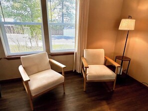 Två fåtöljer, en golvlampa och ett fönster med persienner.