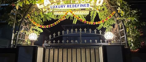 Une entrée sécurisée, fermée par un portail, sur laquelle est apposée une plaque indiquant : « PALACE : LE LUXE RÉINVENTÉ ».