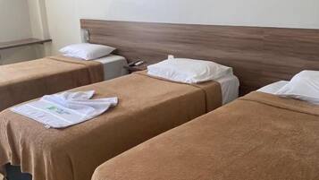 Une chambre d’hôtel avec deux lits simples, chacun recouvert d’une couverture marron et doté d’oreillers blancs.