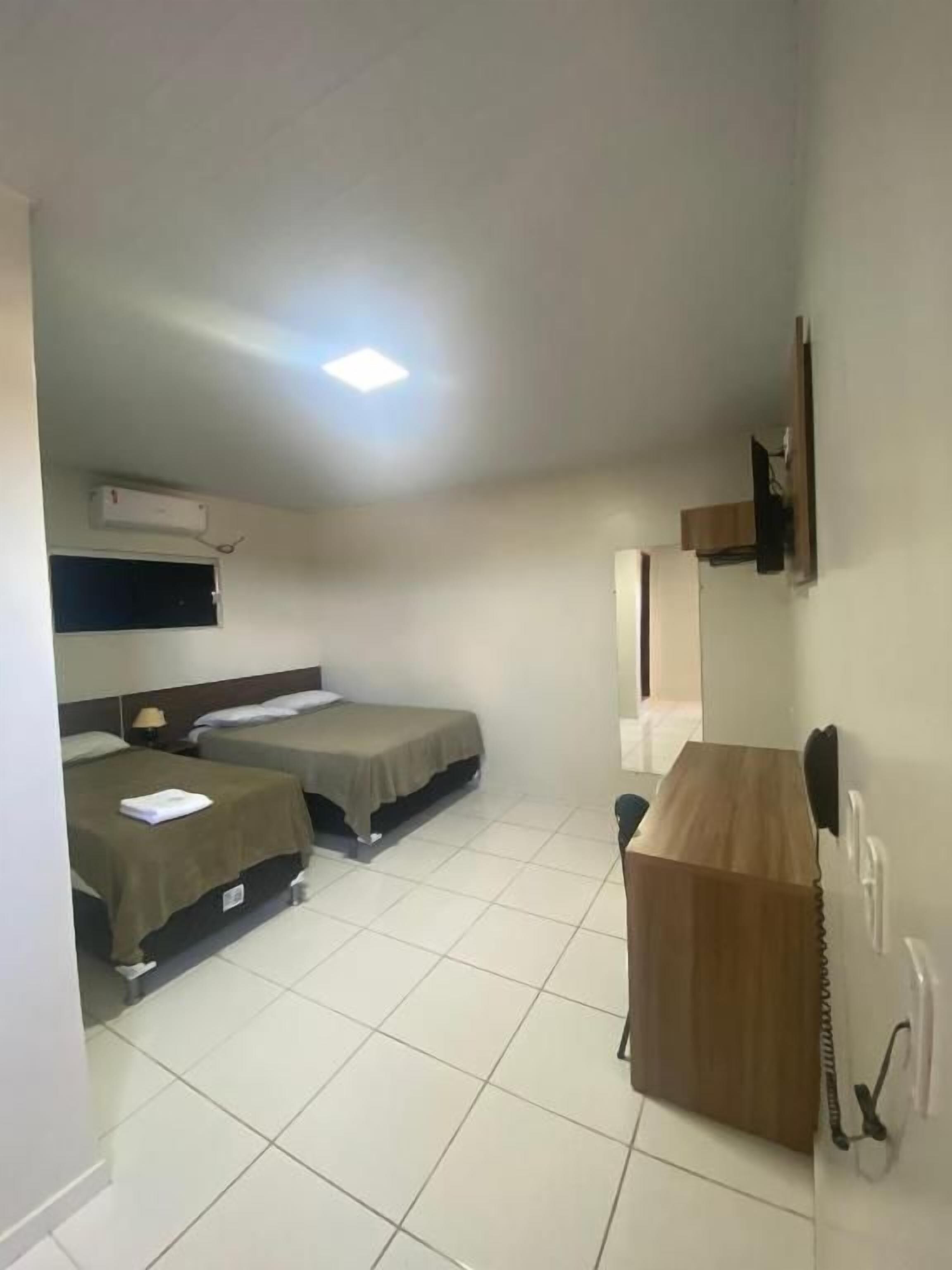 Una habitación con dos camas, un escritorio, una silla y un teléfono.
