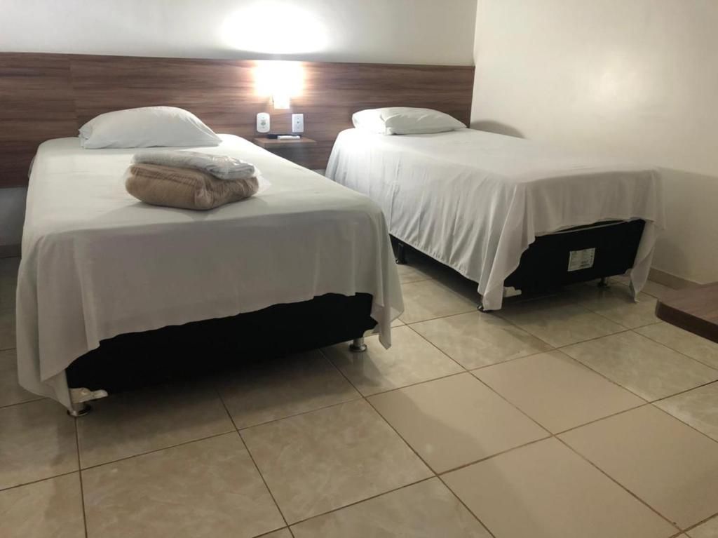 Een hotelkamer met twee bedden, een nachtkastje en een wandlamp.