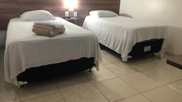 Een hotelkamer met twee bedden, een nachtkastje en een wandlamp.