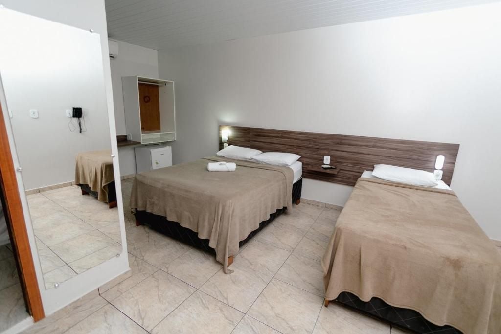 Ein Hotelzimmer mit zwei Betten, einem Spiegel, einem Kleiderschrank und einem Nachttisch.