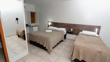 Ein Hotelzimmer mit zwei Betten, einem Spiegel, einem Kleiderschrank und einem Nachttisch.