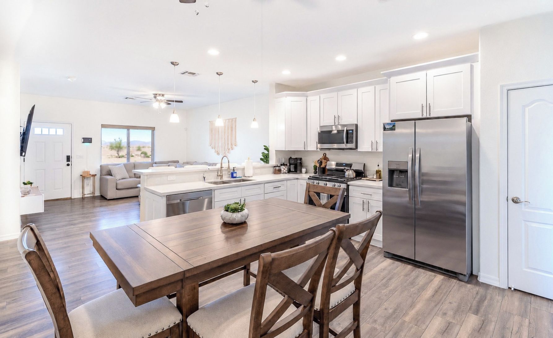 Una cocina moderna con armarios blancos, electrodomésticos de acero inoxidable y una mesa de comedor de madera.