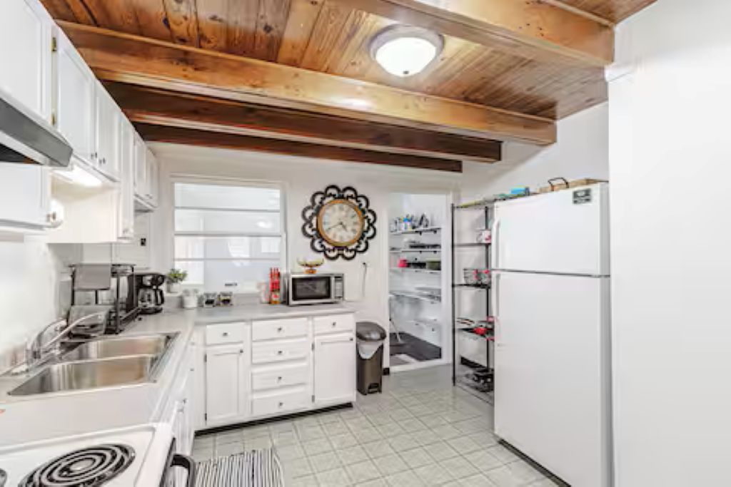 A kitchen with white cabinets, a microwave, a sink, and a refrigerator.