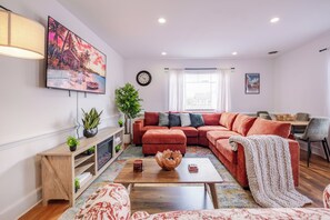 A living room with a sectional sofa, a coffee table, a TV, and a fireplace. - Stylish 2BR apt in beautiful Petersburg w/ parking, laundry, & outdoor space (Petersburg)