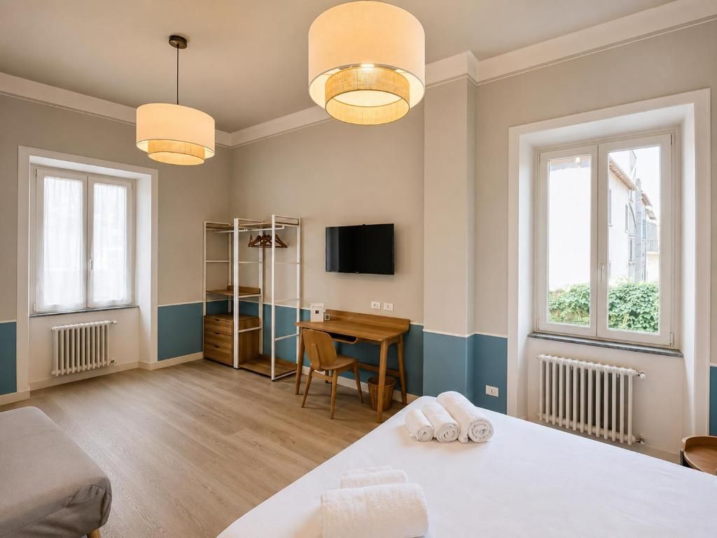 Ein Hotelzimmer mit Bett, Schreibtisch, Stuhl, Fernseher und Kleiderschrank.