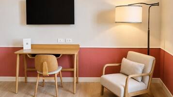 Ein Zimmer mit Schreibtisch, Stuhl und Stehlampe.