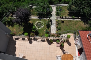 Un jardín en la azotea con un sendero de piedra, plantas en macetas y mobiliario de exterior.