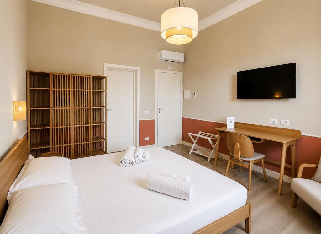 Een hotelkamer met een bed, een bureau, een stoel, een televisie en een kledingkast.
