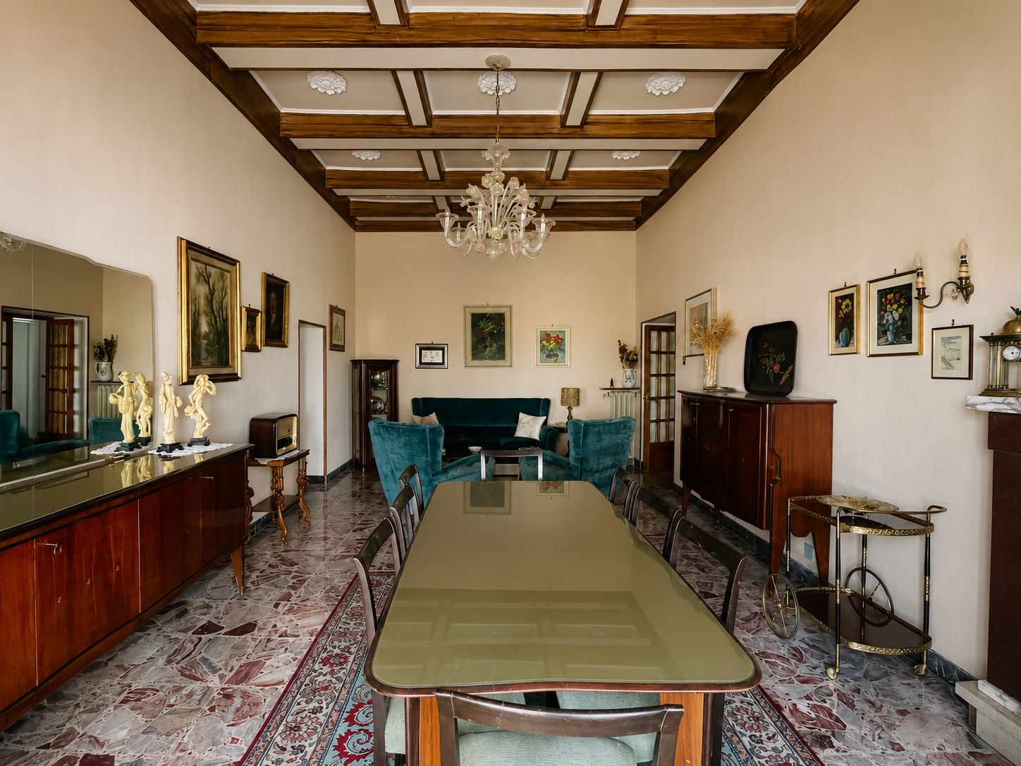 Uma sala de jantar com uma mesa comprida, cadeiras, um candelabro e uma lareira.