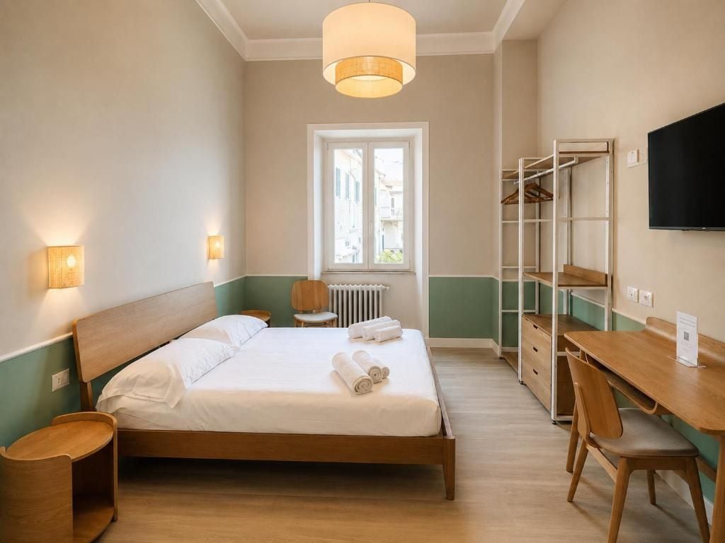 Habitación de hotel con cama, mesita de noche, lámpara, armario y televisión.