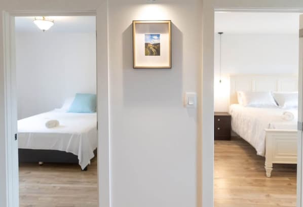 A hotel room with a bed, bedside table, and a framed picture on the wall.