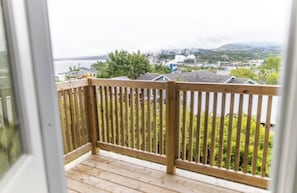 A wooden deck with a view of a residential area and a distant smoke plume.