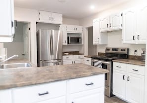 A modern kitchen with white cabinetry, stainless steel appliances, and a granite countertop.