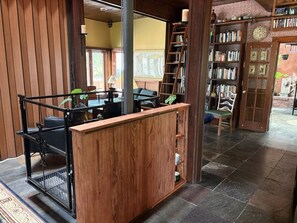 Ein Holzbüro mit Metallgestell, ein Bücherregal und eine Sitzecke mit Tisch und Stühlen.