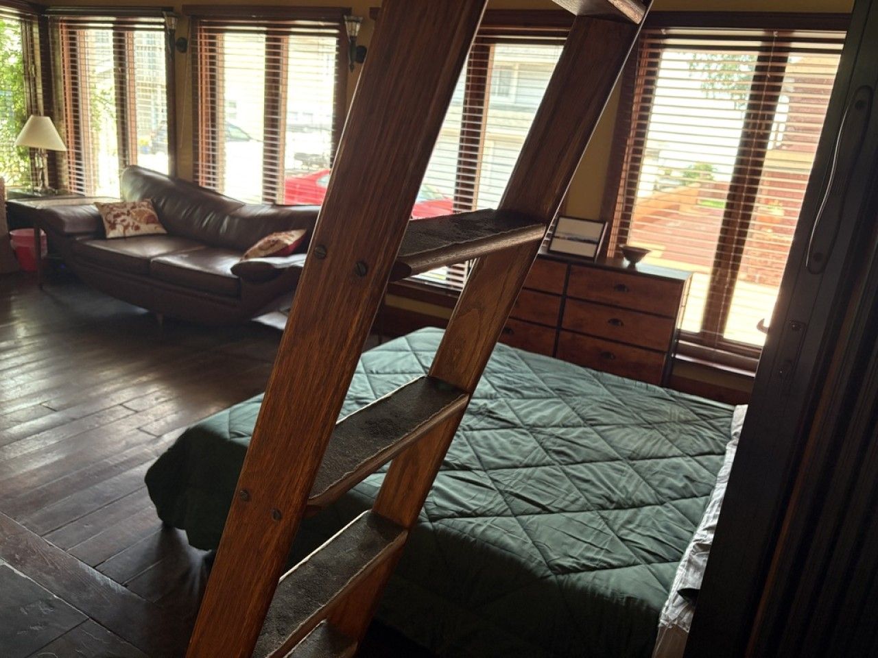 Ein Zimmer mit einem Hochbett, einer Schlafcouch und einer Holzleiter.