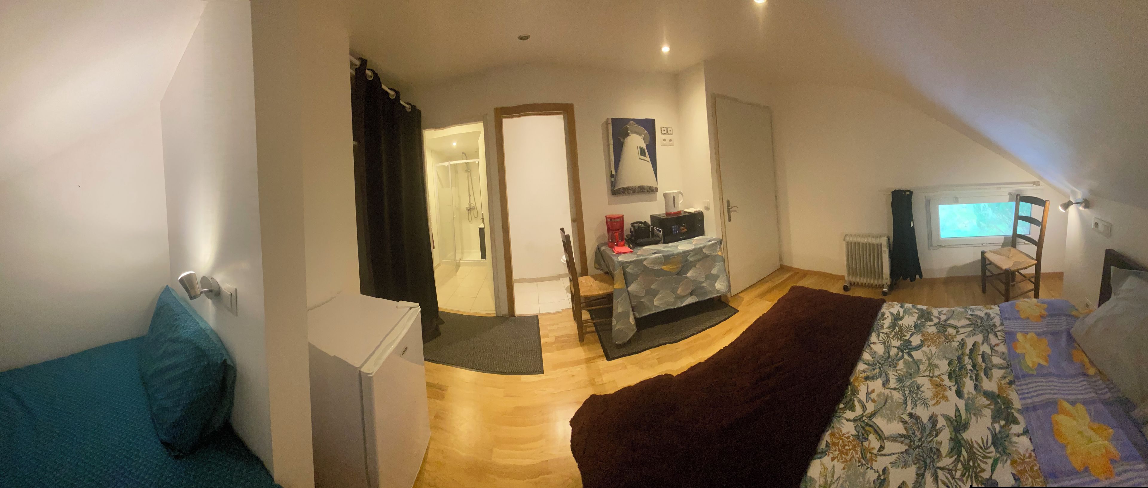 A bedroom with a bed, a desk, a chair, a radiator, and a window.