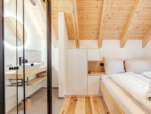 A modern bedroom with a wooden ceiling, a bed, a nightstand, and a built-in wardrobe. - Cabin in Niederwolz With Sauna (Oberwölz)