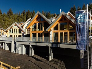A row of wooden cabins with large windows, a covered walkway, and a banner with text. - Cabin in Niederwolz With Sauna (Oberwölz)