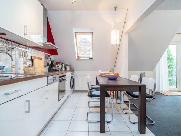 A modern kitchen with a dining area, a window, and a view of the outdoors. - Ohana Holiday Apartment (Zingst)