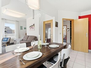 Ein Essbereich mit einem Holztisch, gedeckt für zwei Personen, weißen Stühlen und einer Champagnerflasche.