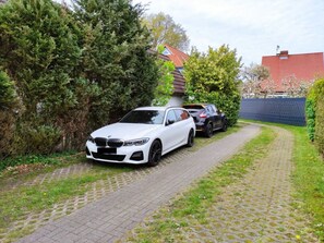 Une allée pavée mène à une voiture blanche garée sur le bord de la route.